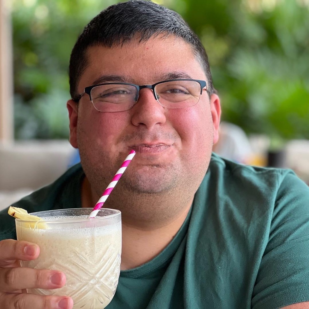 A photo of me in Cancun, smiling and drinking a piña colada.